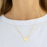 Delicate gold heart necklace worn by a person on a white background