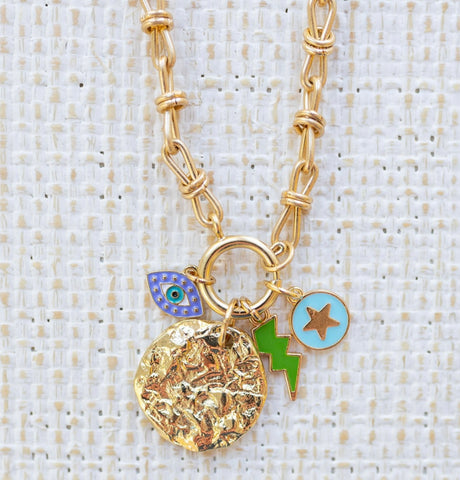 Picture of gold toggle chain with four charms attached. Charms include evil eye, green lightening bolt, blue disc with gold star in center and large gold textured disc.