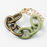 Bracelet with large gold and green chain links on a white background