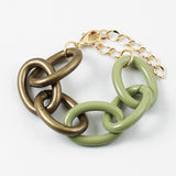 Bracelet with large gold and green chain links on a white background