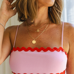 Girl smiling looking away wearing multiple gold layered necklaces with a gold circle medallion in the middle with a paperclip link chain around her neck