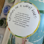 Round card with text on a magazine surface with small containers and beads