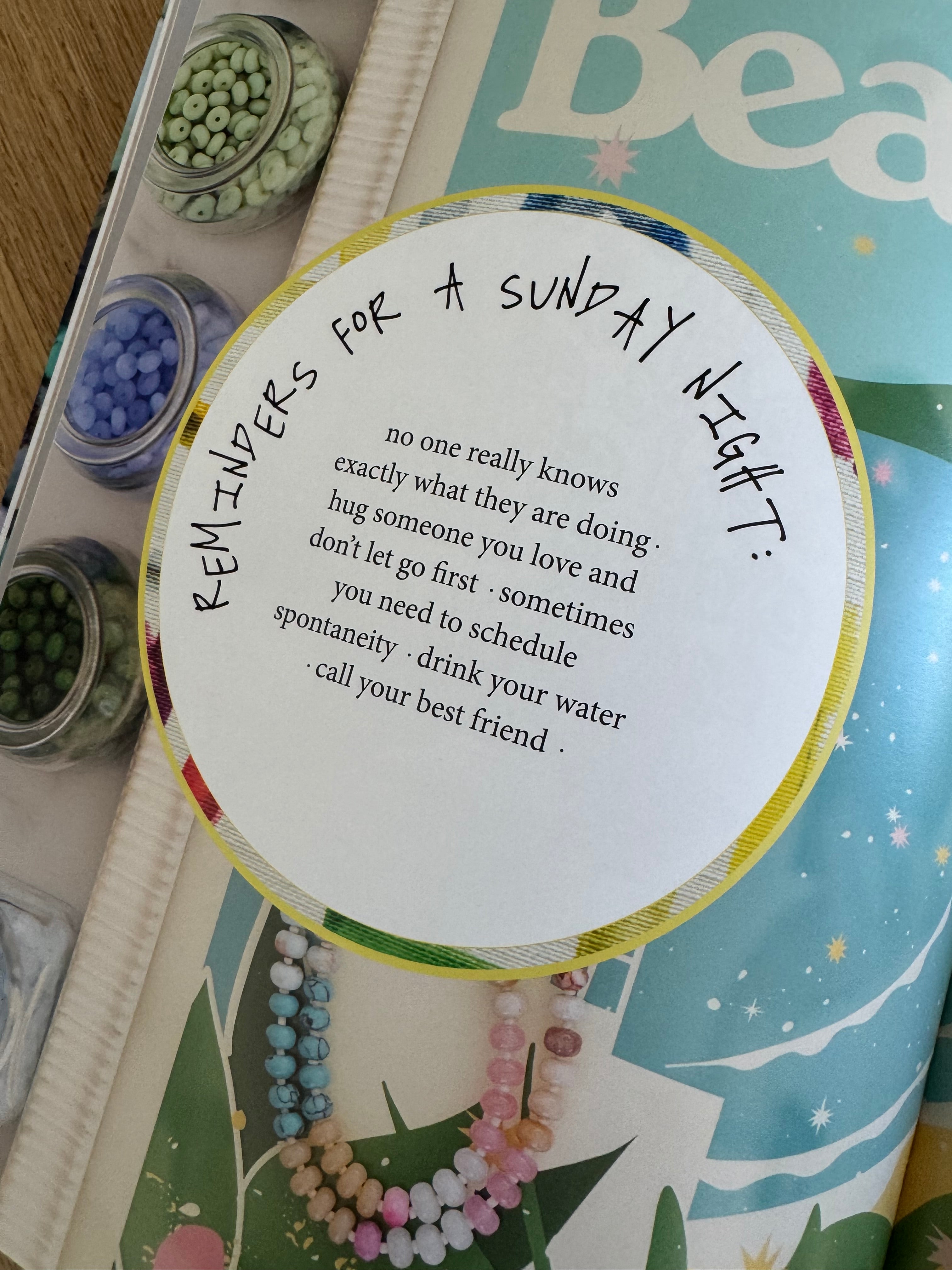 Round card with text on a magazine surface with small containers and beads