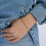 Model's wrist displaying two tiny gold bead bracelets.