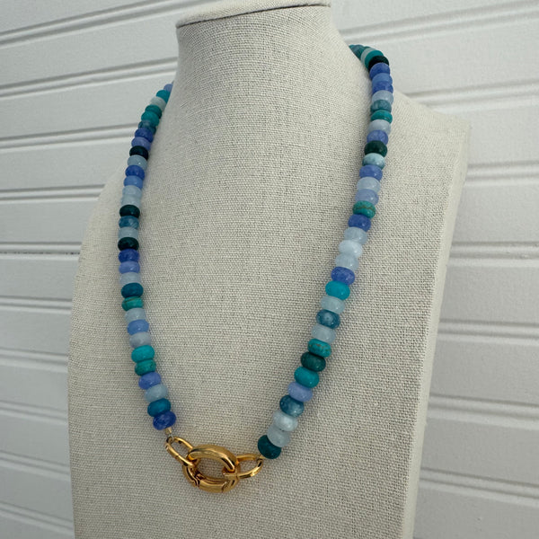 Necklace in shades of dark and light blue beads with a gold clasp.
