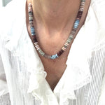 Necklace with multicolored beads worn by a person in a white shirt.