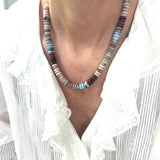 Necklace with multicolored beads worn by a person in a white shirt.
