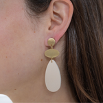 Gold and White dangle earrings. Earrings have a small gold circle base, a small oval and large white teardrop beads at the base.