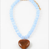 Necklace with light blue beads and a dark amber heart pendant on a white background
