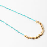Blue bead necklace with gold beads at it's center.