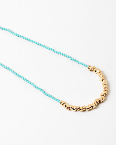 Blue bead necklace with gold beads at it's center.