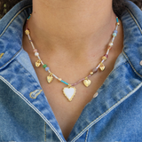 Bead necklace in blues, whites, beige and 4 gold heart pendants and white enamel heart pendant.