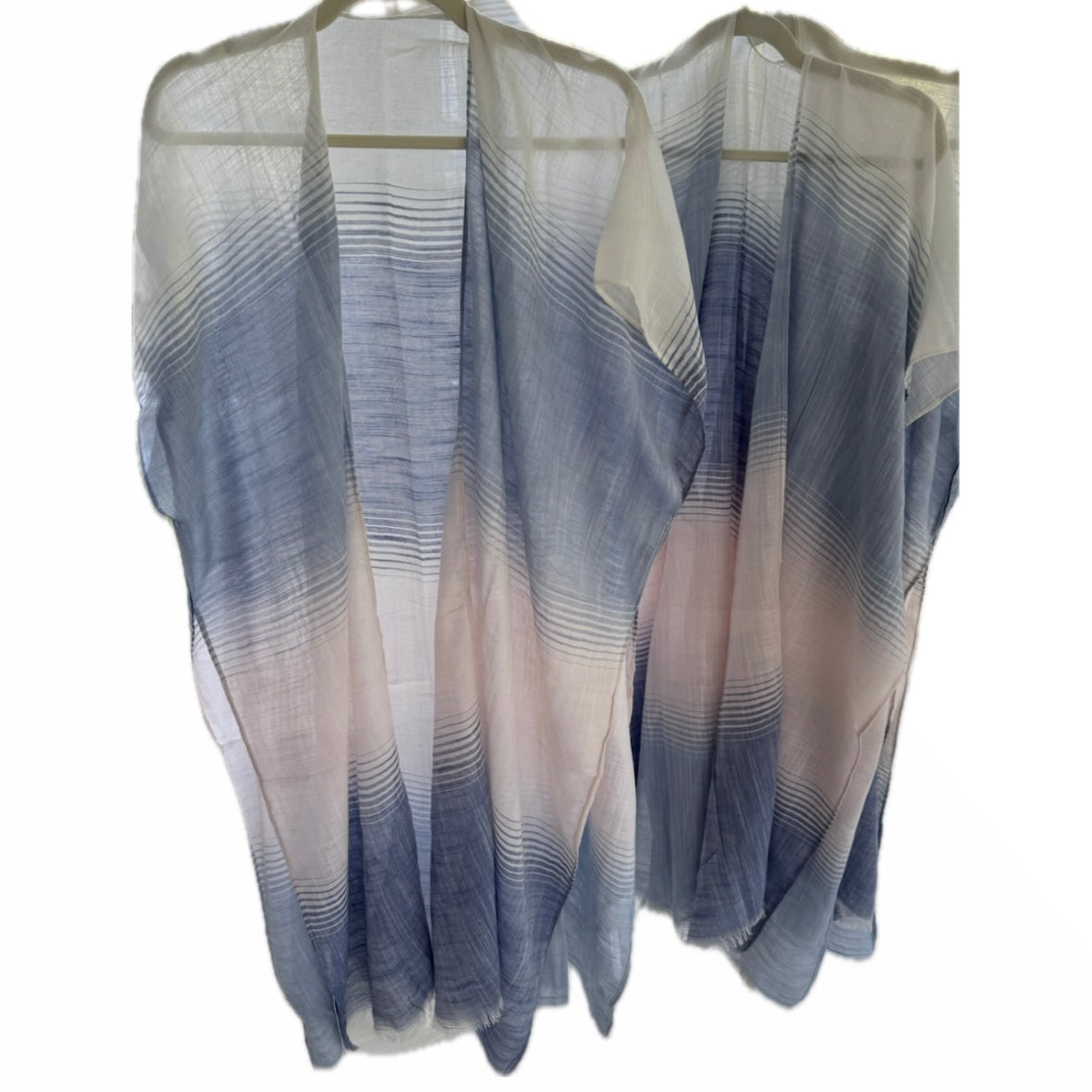Sheer blue and white striped top on a hanger against a white background