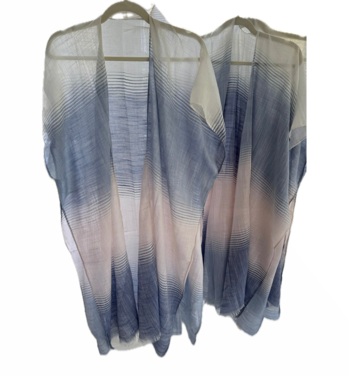 Sheer blue and white striped top on a hanger against a white background