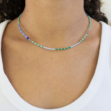 Dainty bead necklace in blues and greens on a woman's neck.