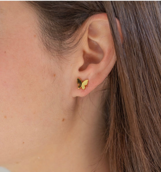Picture of model wearing a gold butterfly earring studs.