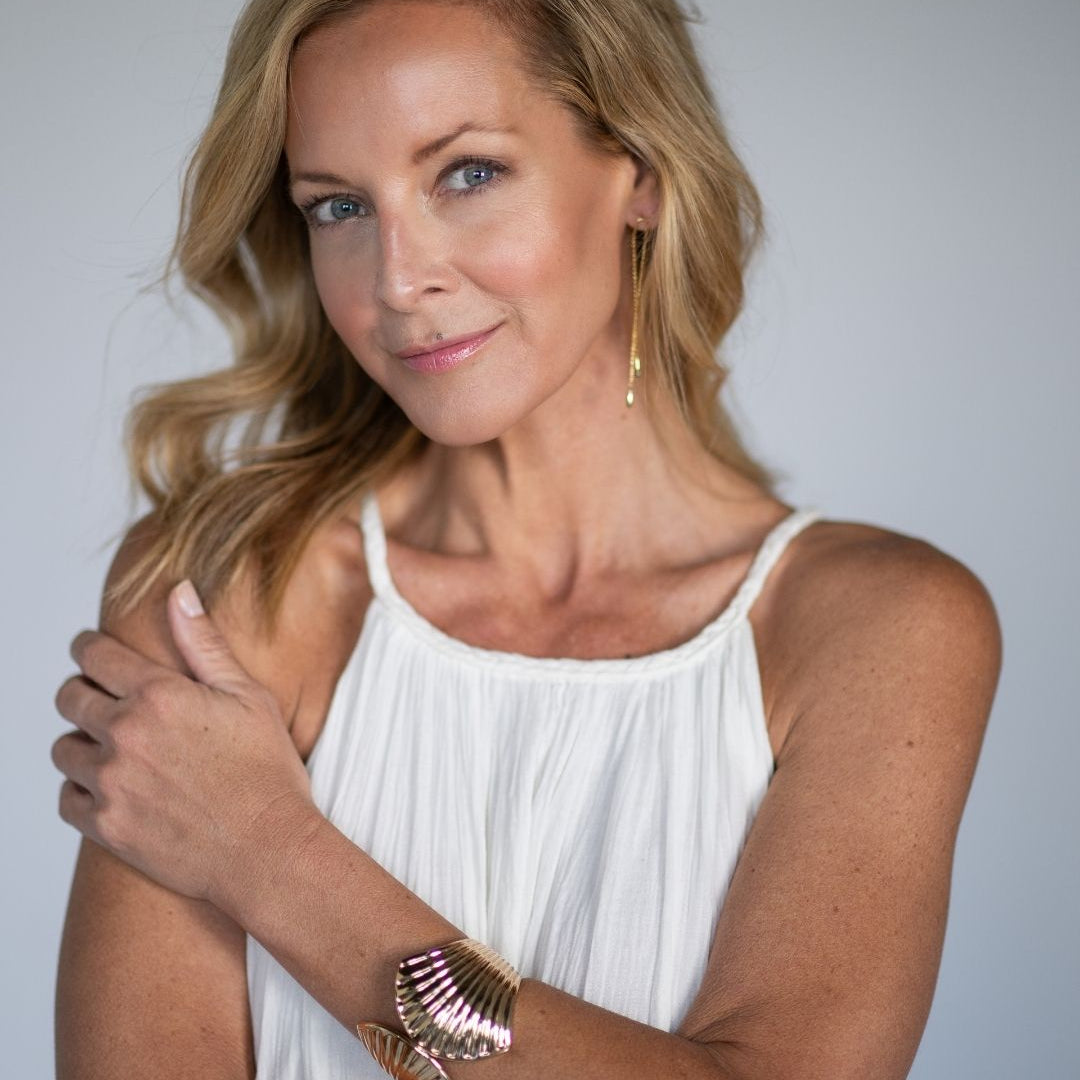 Woman wearing a white sleeveless top with a plain background