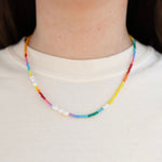 Picture of model wearing a multicolored necklace made of small beads and freshwater pearls.