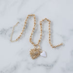 Picture of gold toggle chain with a large gold heart pendant with a diamond at its center and a white heart charm.