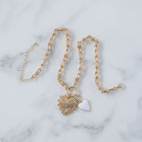 Picture of gold toggle chain with a large gold heart pendant with a diamond at its center and a white heart charm.