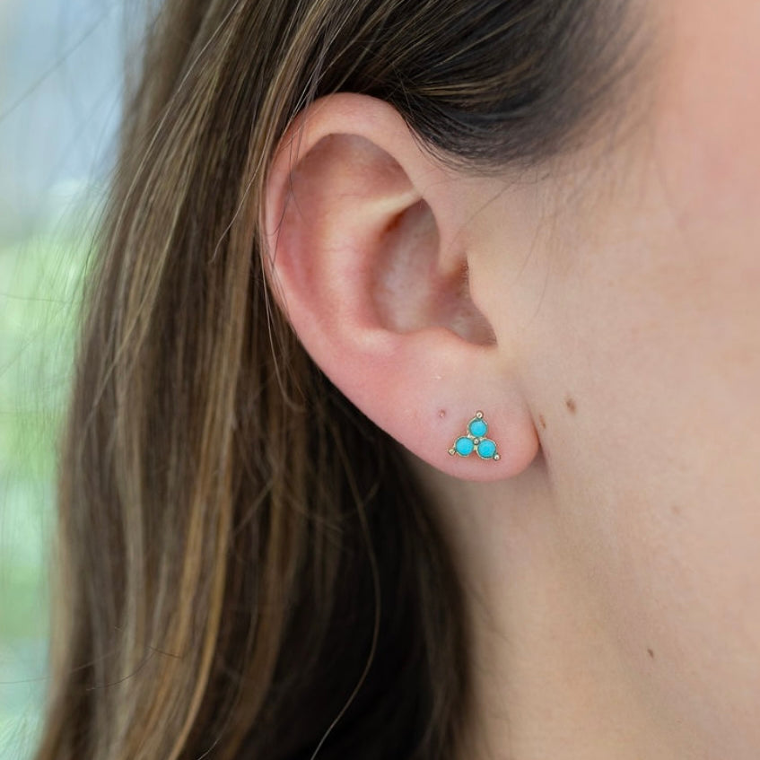 Picture of a model's ear displaying a three stone turquoise stone stud earrings.