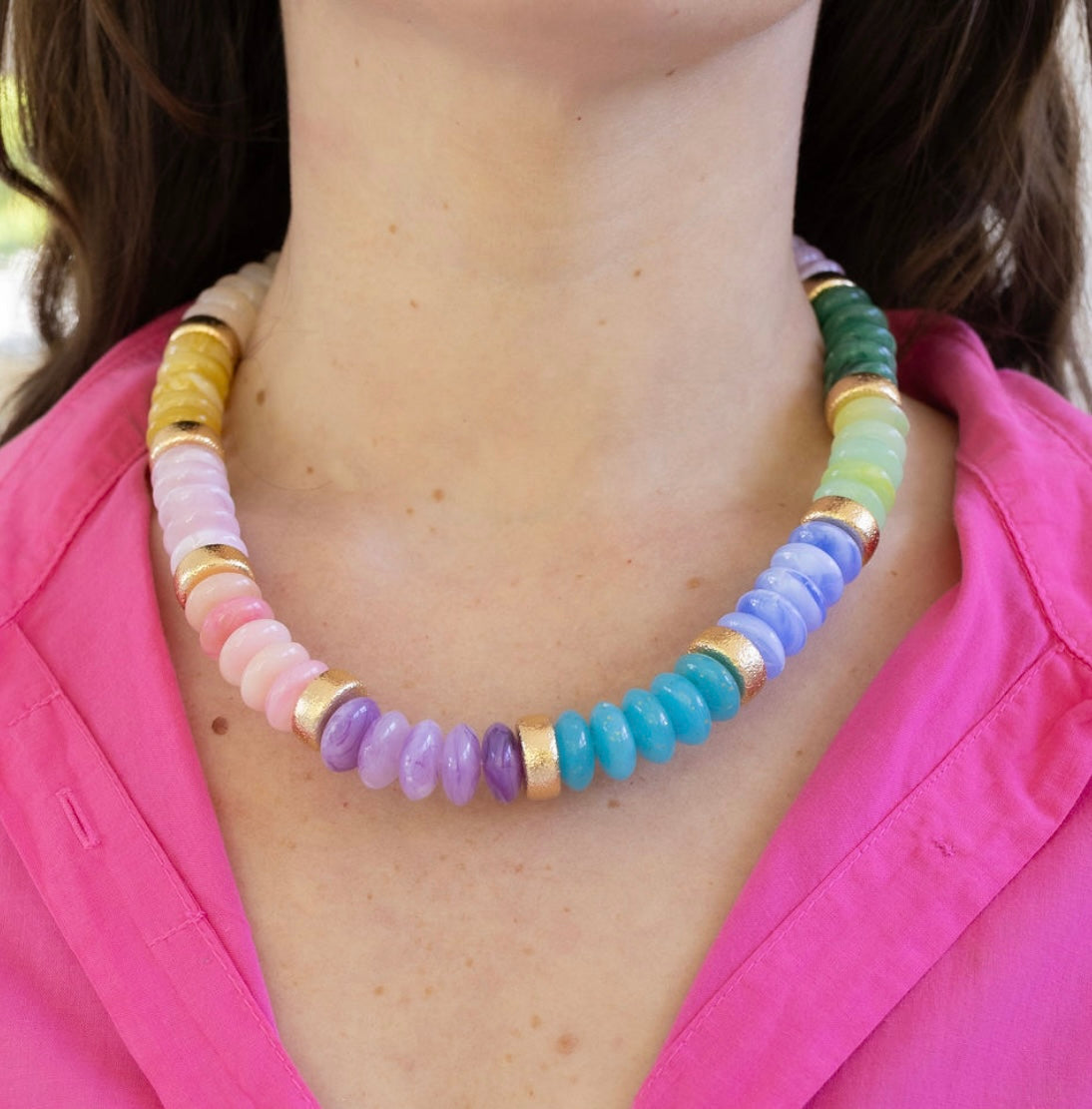 Colorful chunky beaded necklace worn by a person with a pink shirt