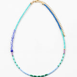 Dainty bead necklace in light blue, green and teal beads with some larger dark blue and striped beads.
