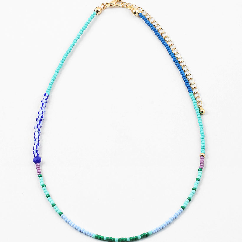 Dainty bead necklace in light blue, green and teal beads with some larger dark blue and striped beads.