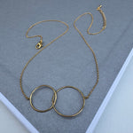 Delicate gold chain with two large gold hoops linked together at its center.