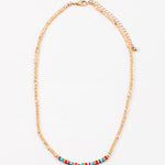 Dainty gold bead necklace with small red, yellow and turquoise beads at its center.