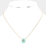 Gold necklace with a turquoise donut pendant on a white background