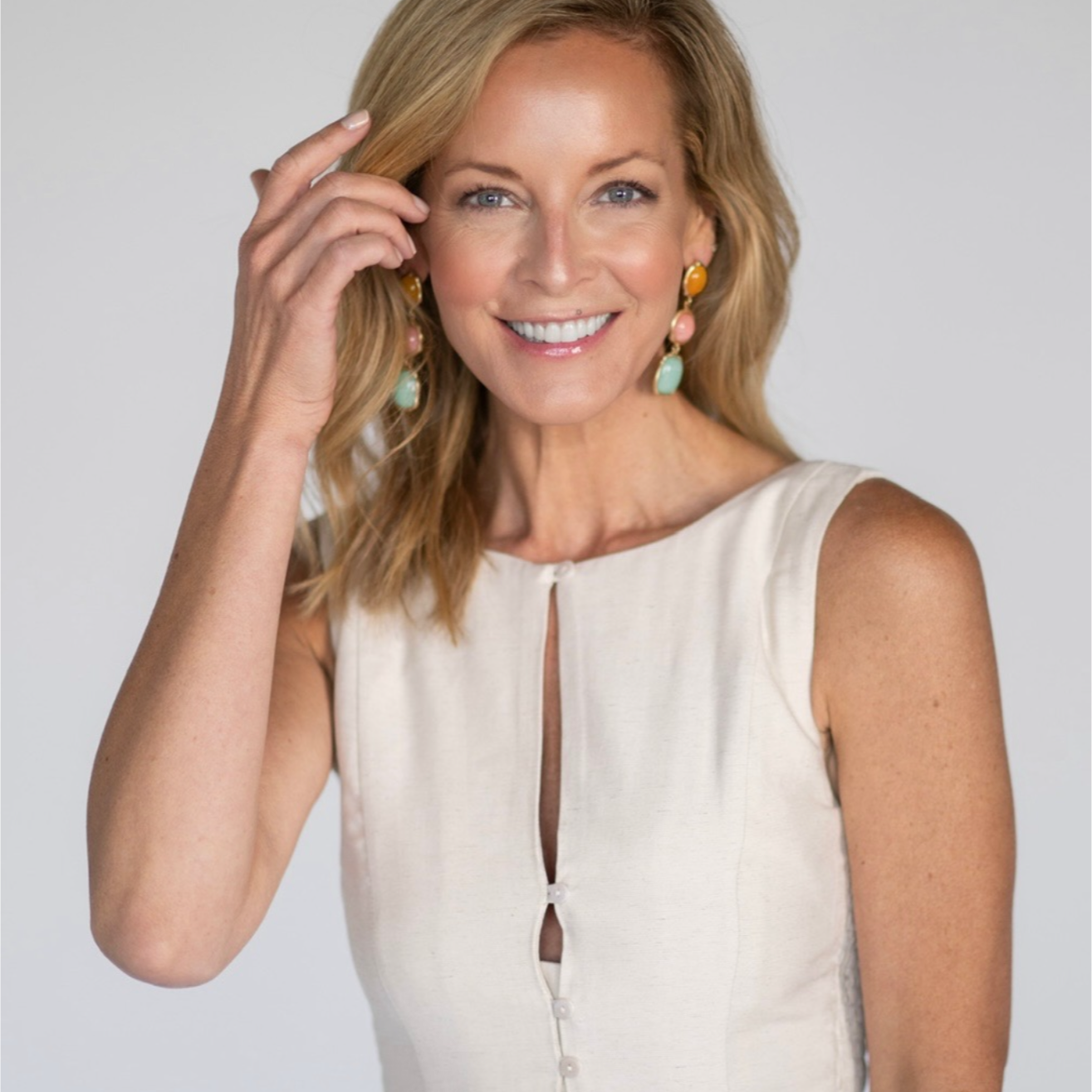 Woman wearing a white sleeveless top against a plain background