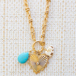 Picture of gold toggle chain with a large gold heart pendant with a diamond at the center.  Also attached is a blue marbled teardrop bead and white elephant.