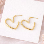 Gold heart-shaped earrings on a white card