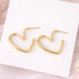 Gold heart-shaped earrings on a white card