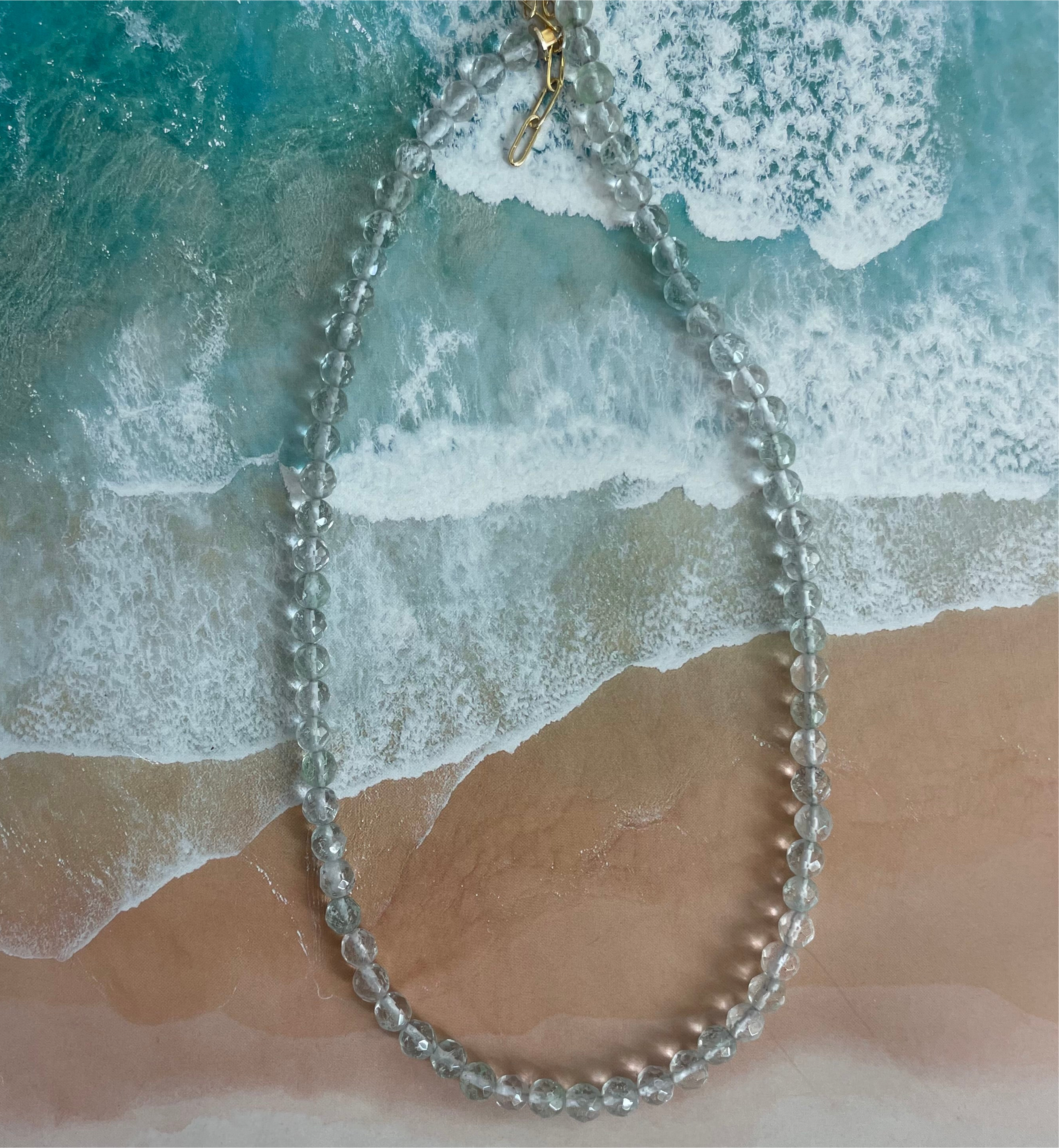 Clear bead necklace on a beach with waves in the background