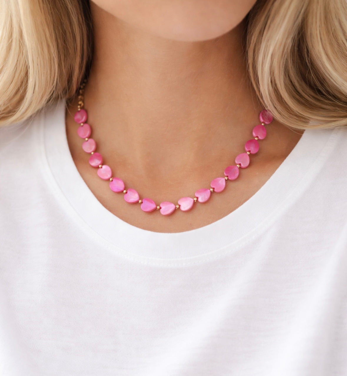 Pink heart beaded necklace worn by a person on a white background