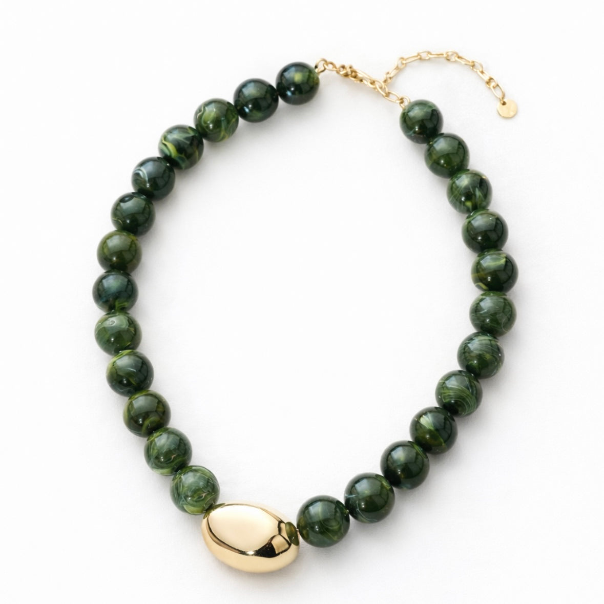 Green beaded necklace with a large central gold bead with a gold clasp on a white background.