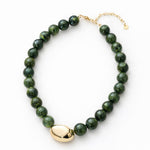 Green beaded necklace with a large central gold bead with a gold clasp on a white background.