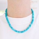 Turquoise beaded necklace worn by a person on a white background