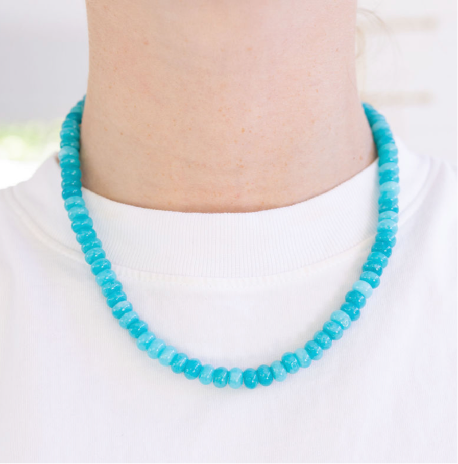Turquoise beaded necklace worn by a person on a white background
