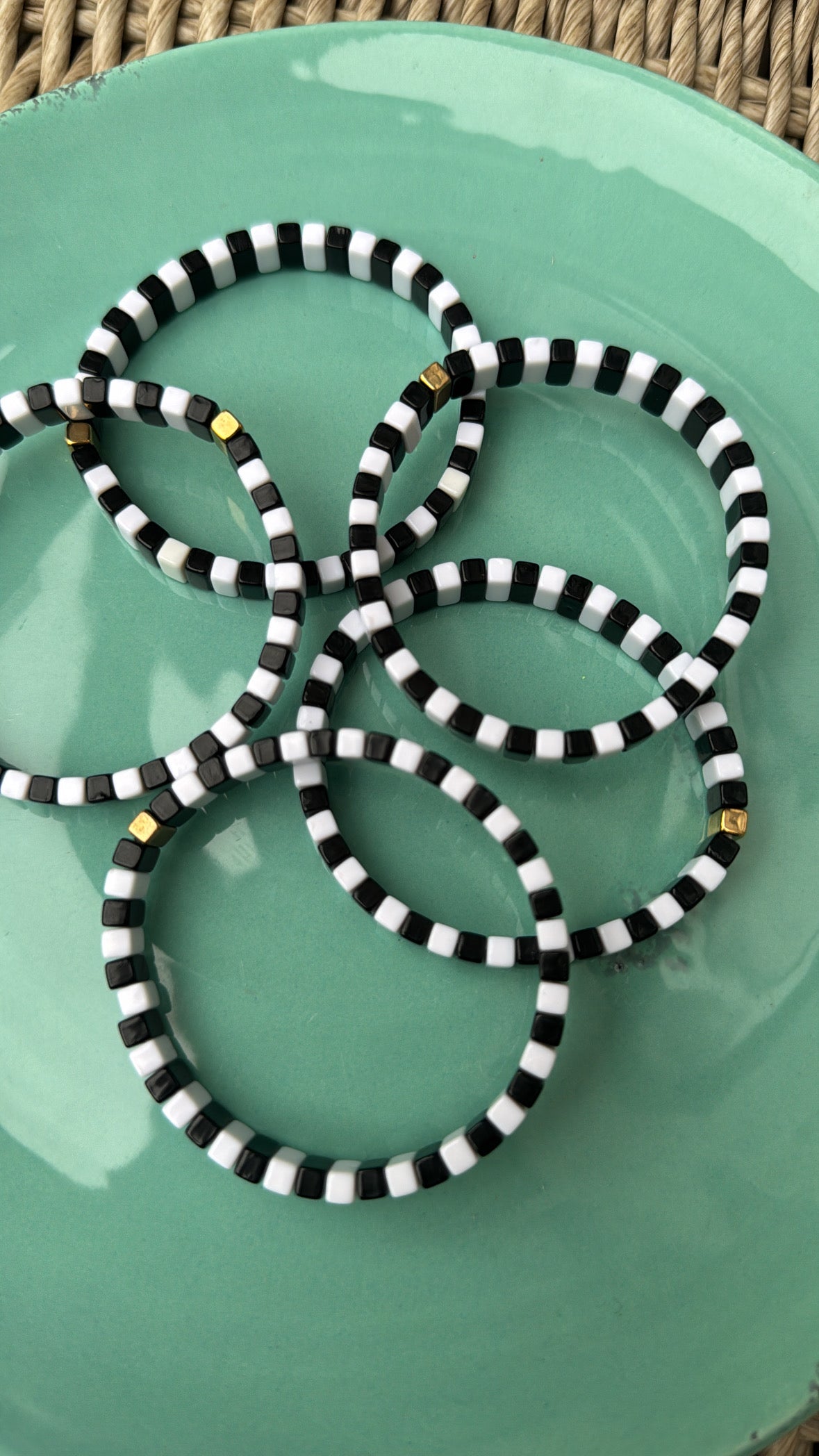 Picture of a green plate containing 5 black and white monochrome bracelets