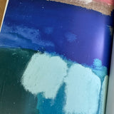 Close-up of a book page featuring a picture of a textured surface with blue, green, and white colors.