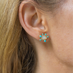 Girl wearing small earrings with a white/gold stone circular shape with tiny blue circular stones around it