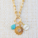 Picture of gold toggle chain with various charms attached.  One is a turquoise tear drop charm, gold textured disc with diamond heart in the center and white 11:11 disc.