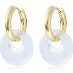 Set of small gold hoop earrings with opaque white hoops through them.