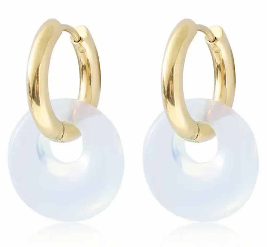 Set of small gold hoop earrings with opaque white hoops through them.