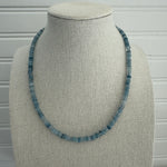 Picture of a display showing a blue bead necklace in different shades.