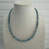 Picture of a display showing a blue bead necklace in different shades.