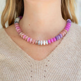 Necklace with multicolored pink and purple beads worn by a person in a beige sweater.
